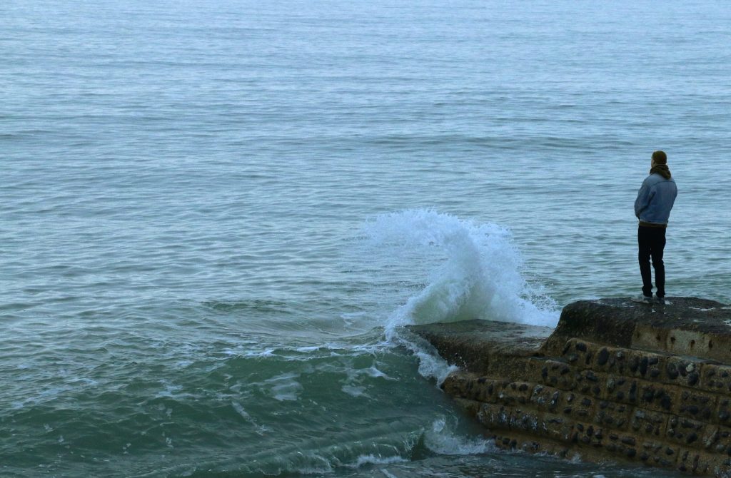 Man standing on a shoreline, suffering from PTSD symptoms.